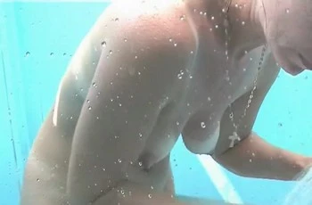 На пляже голая женщина купается в душе
